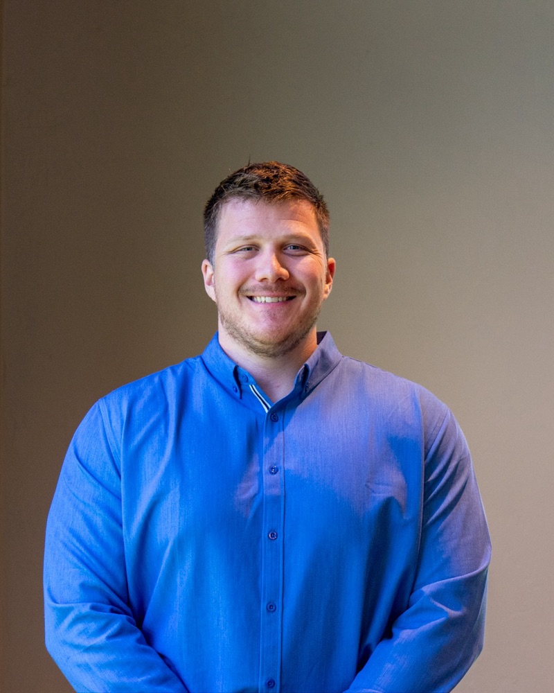 Adam Schapekahm, smiling, in a blue button-down shirt.